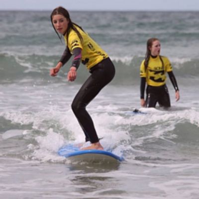 two young girls in the water learning to surf dingle peninsula Ireland